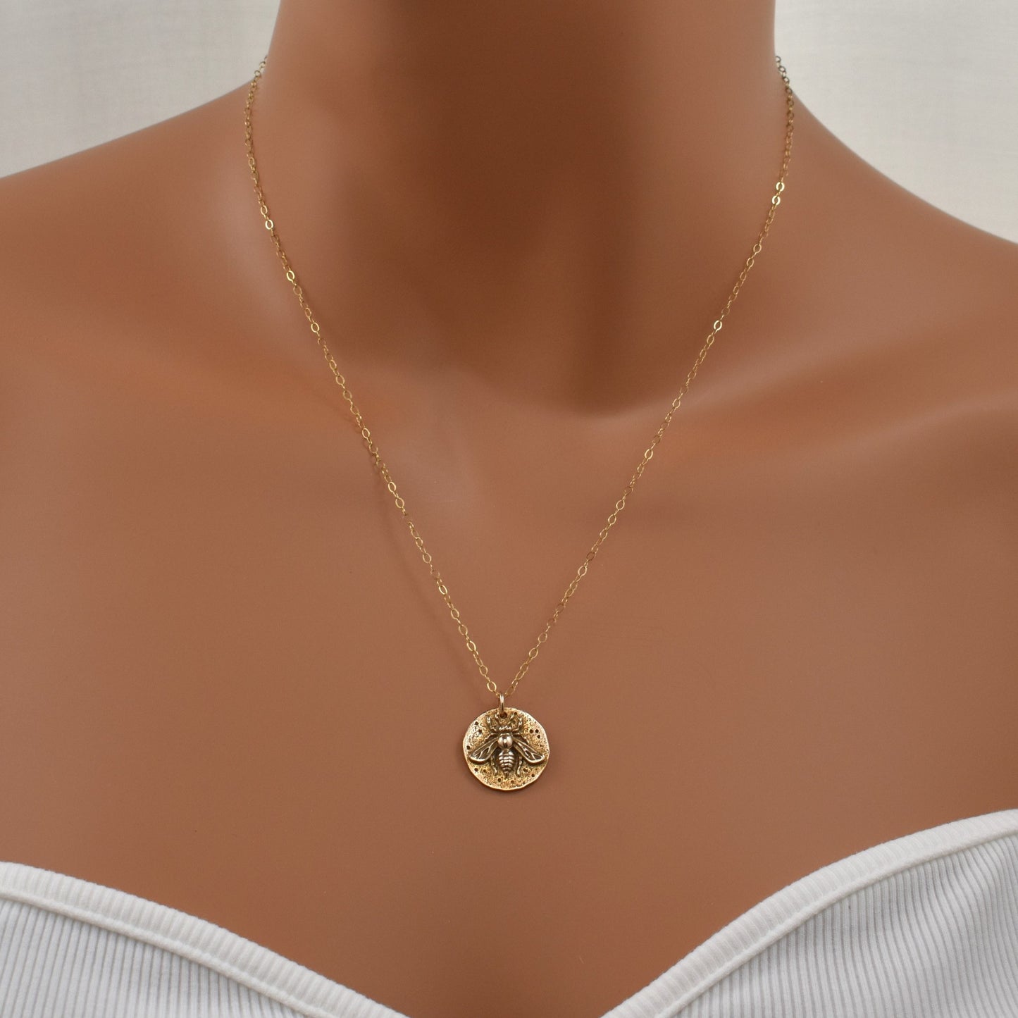 Gold bee pendant necklace shown on model.