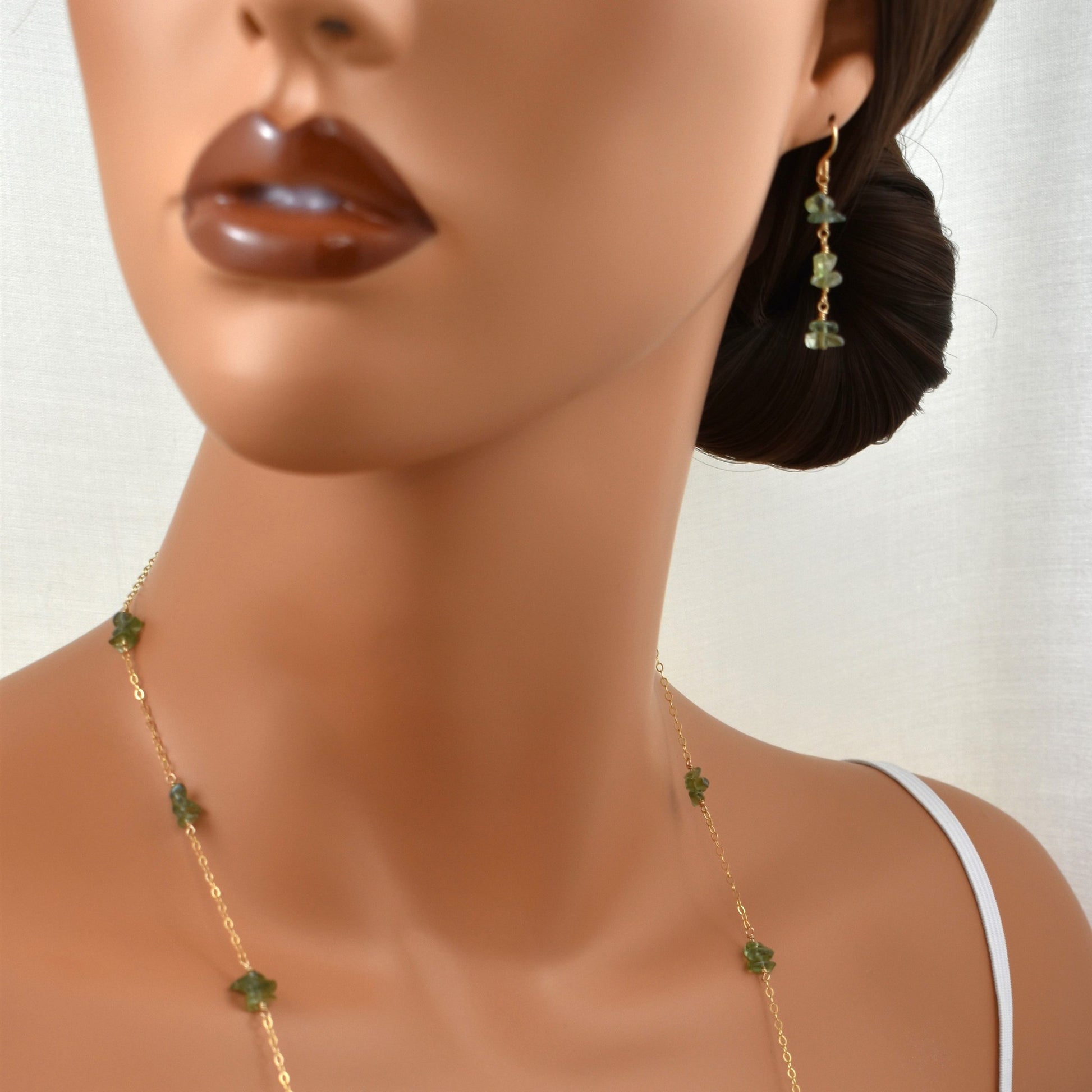 Green apatite gemstone dangle earrings on model.