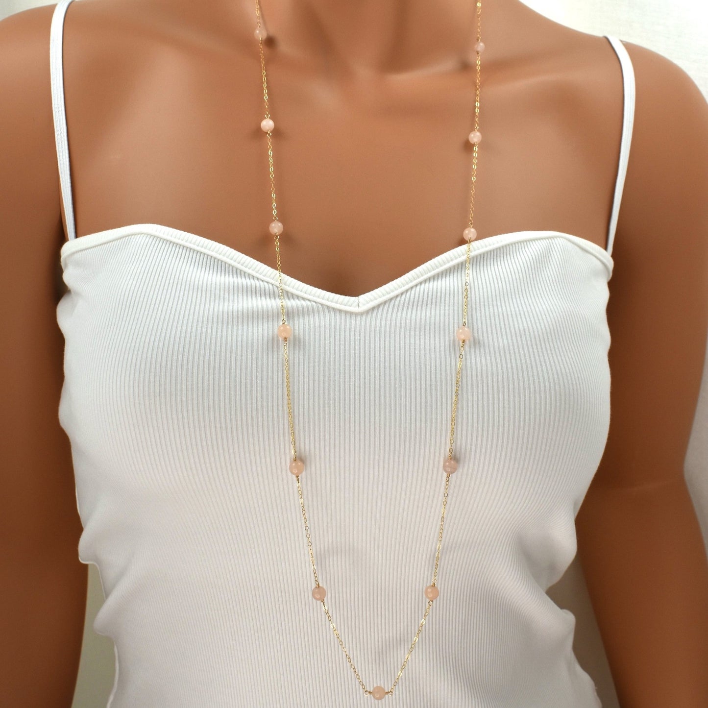 Long gold necklace with pink peach quartz gemstones, 38 inches long.