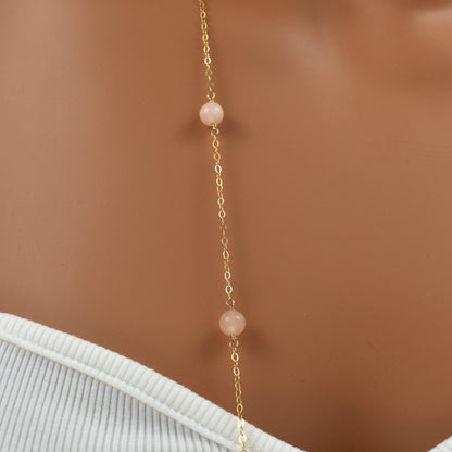 Long gold necklace with pink peach quartz gemstones, 38 inches long, close up.