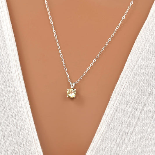 Light yellow citrine gemstone pendant in a four-prong setting strung on a sterling silver chain.