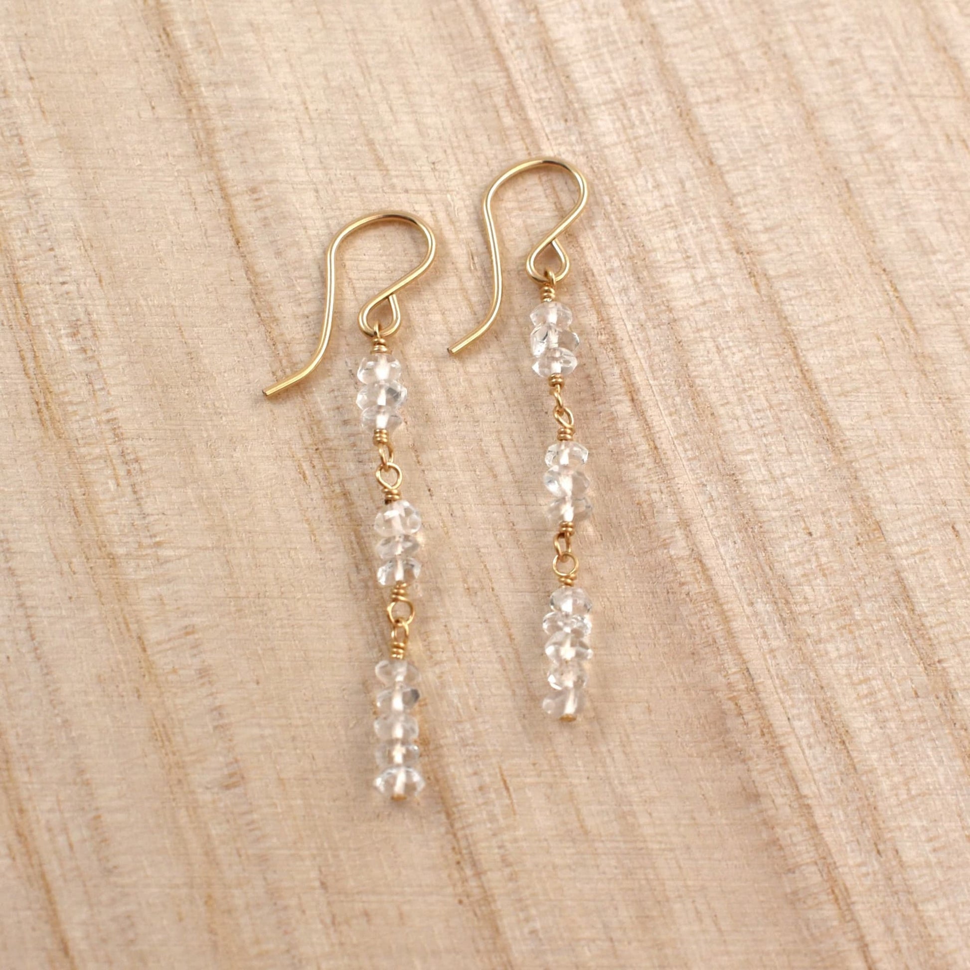 Clear quartz crystal dangle earrings in gold.