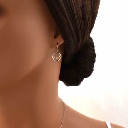 gold and silver circle drop earrings shown on model.