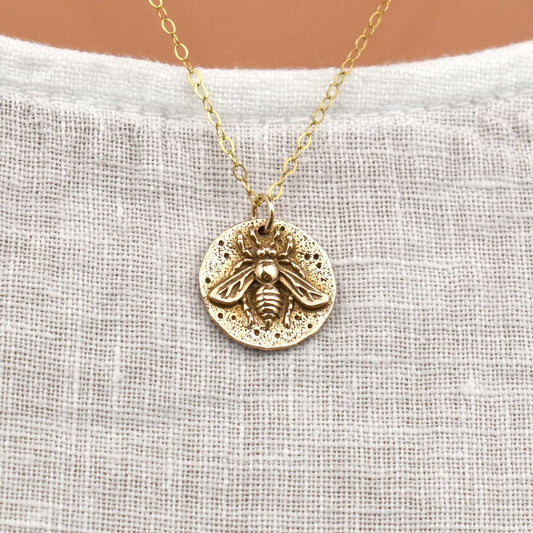 Gold bee pendant necklace close up.