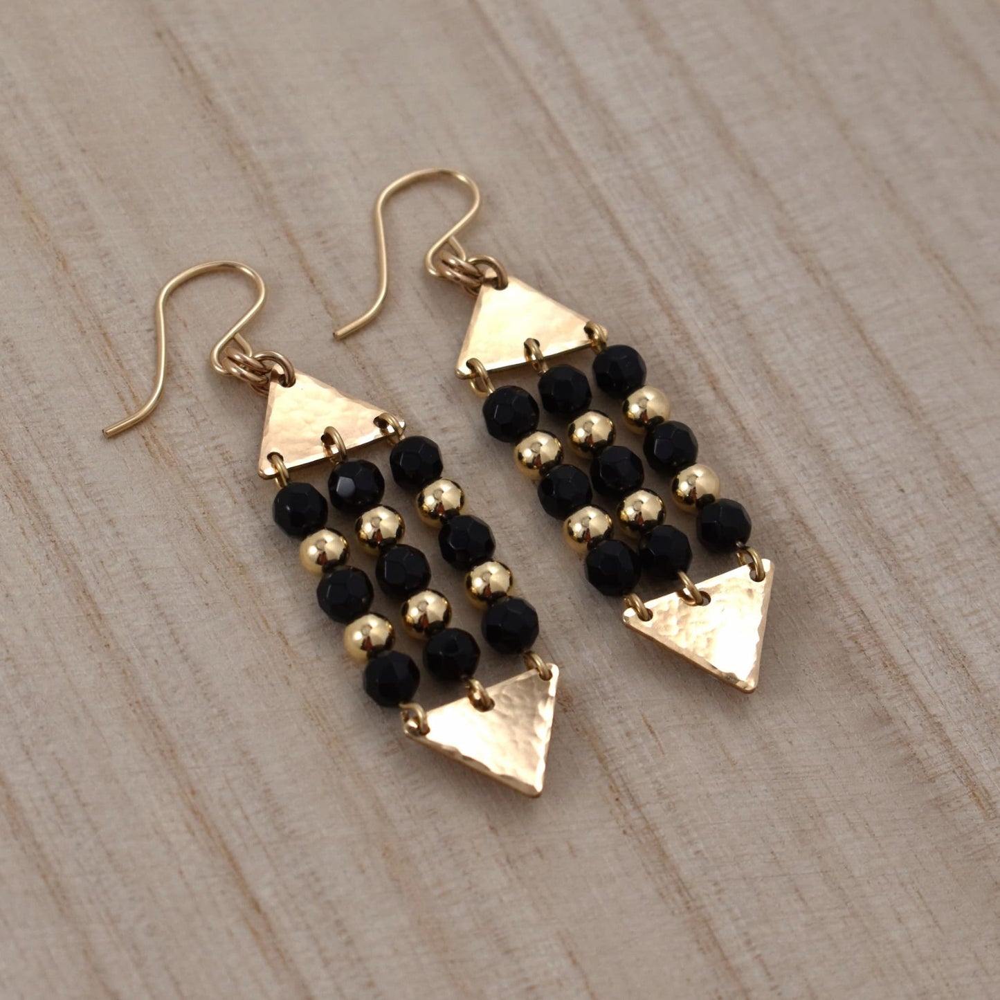 Gold triangle dangle earrings with black onyx gemstones.