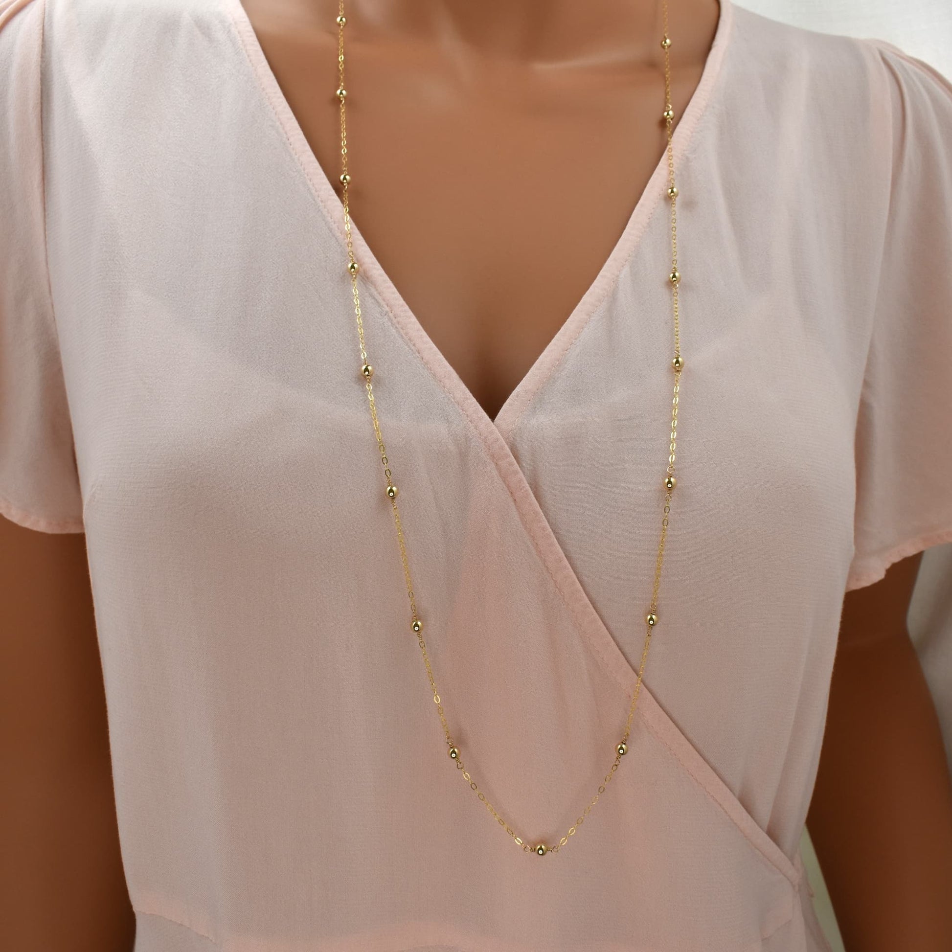 long gold necklace with evenly spaced gold beads on a fine chain.