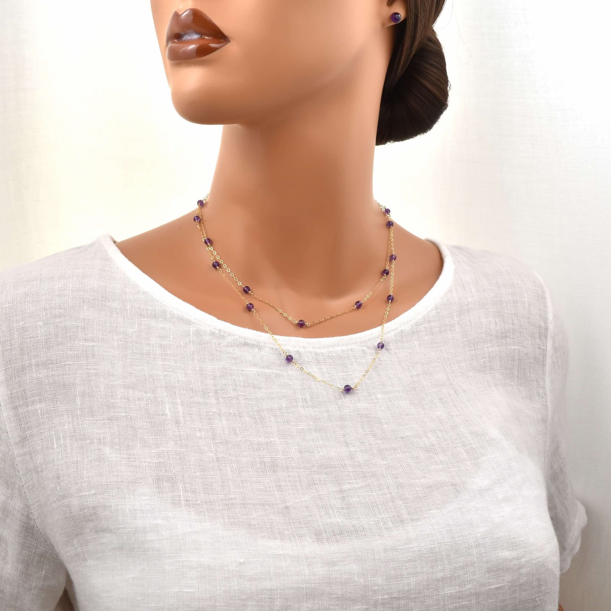 long gold necklace with small amethyst beads, 36 inches long shown on a female model wrapped around the neck twice for a layered look.