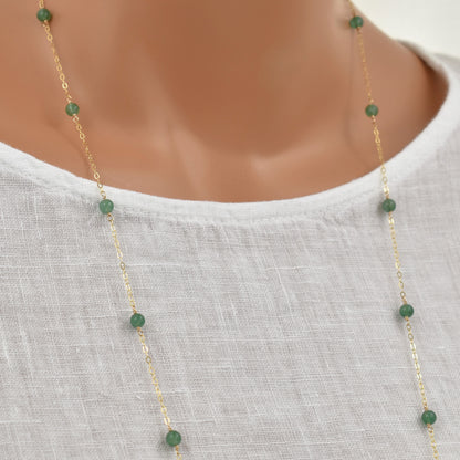 Long gold necklace with green aventurine beads close up