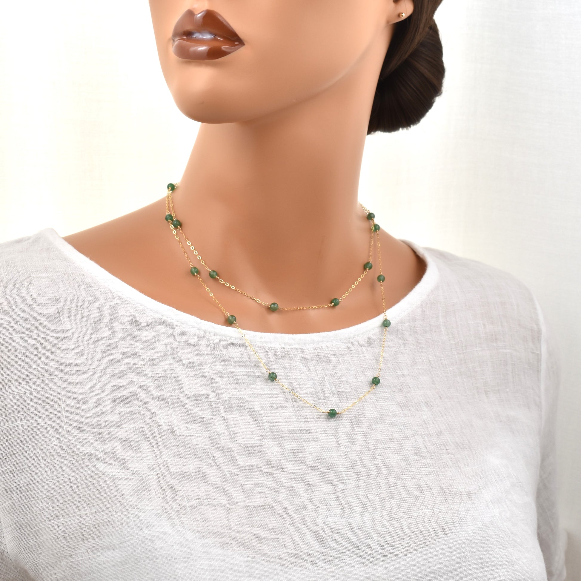 Long gold necklace with green aventurine beads, 36 inches long shown on a female model wrapped twice around the neck for a layered look.