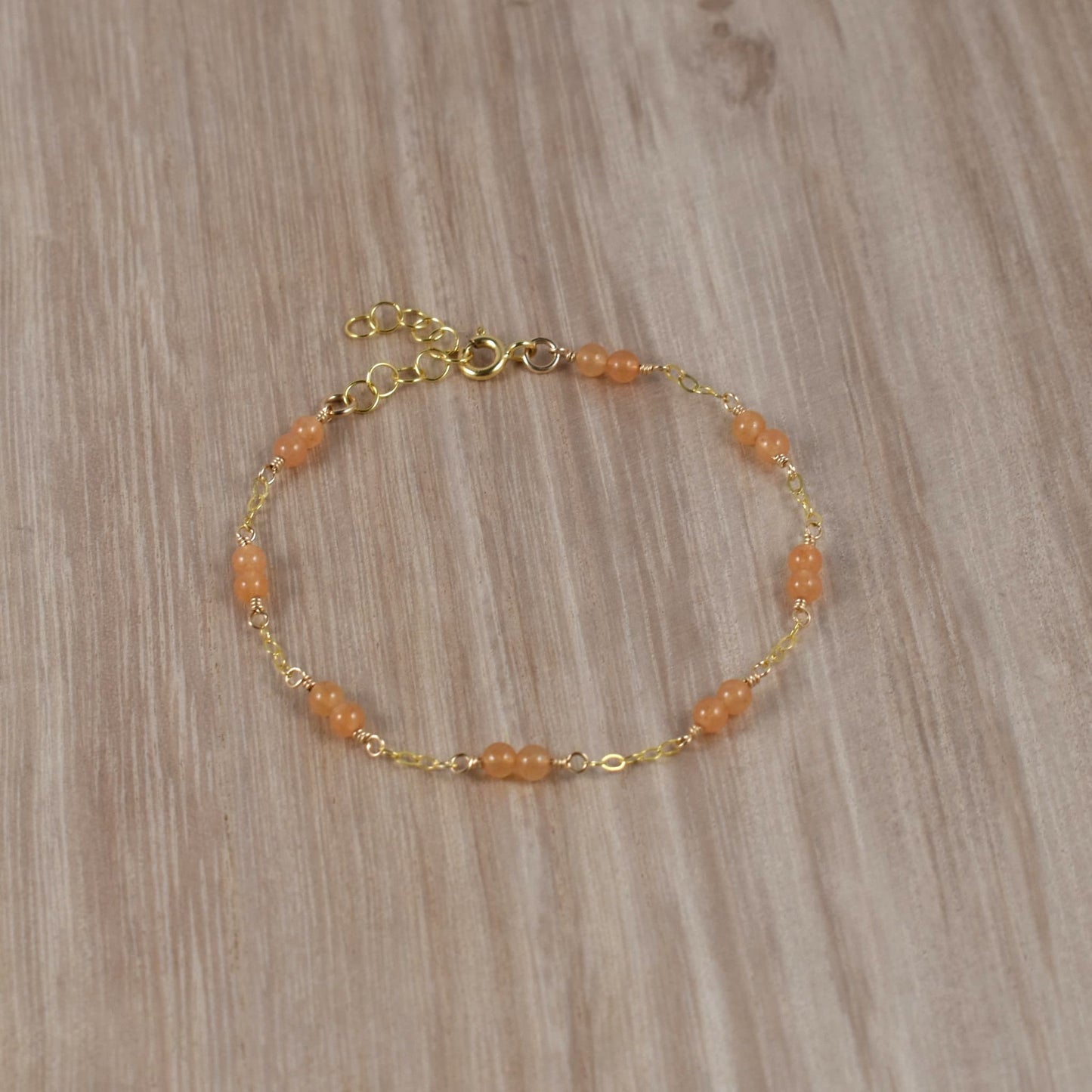 Orange aventurine bead bracelet with gold chain.