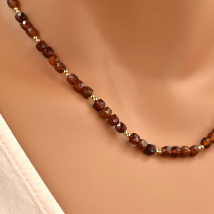 Red hessonite garnet necklace with gold beads close up.