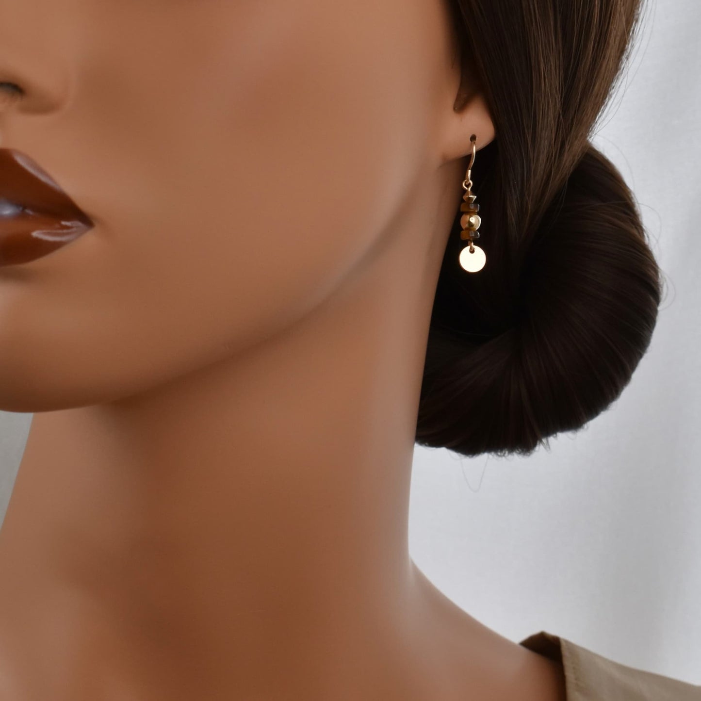 Small gold drop earrings with tiger's eye gemstones shown on model.